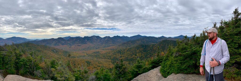 scholcommlab researcher Anton Ninkov looks out at wide view of mountains and trees at Adirondack High Peaks, upstate New York. 