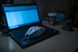 A medical mask sits atop a laptop