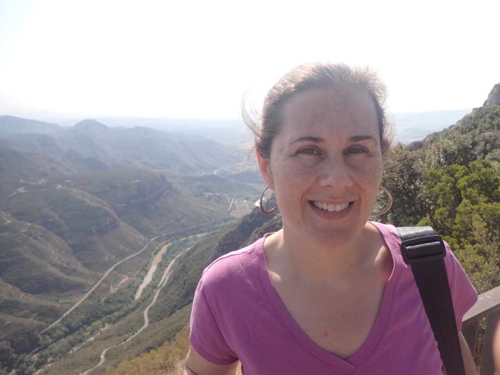 Scholarly Communications Lab member Lauren Maggio smiles for the camera in front of a beautiful view