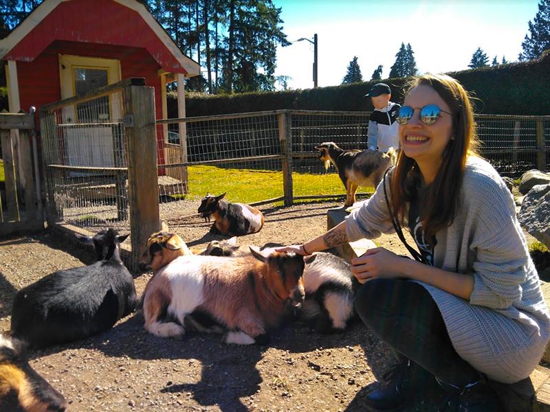 Lisa Matthias, Scholcommlab visiting scholar, crouches down to pet a baby goat at Maplewood Farm, North Vancouver